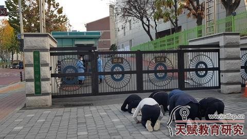 11月17日，韩国数名高中生在高考考场前磕头应援。（纽西斯通讯社）